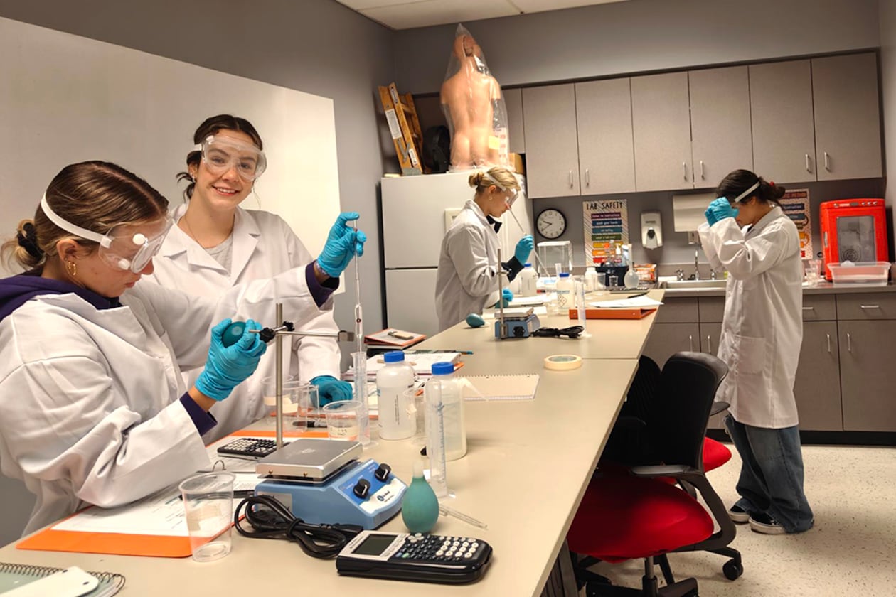 Students work in white lab coats.