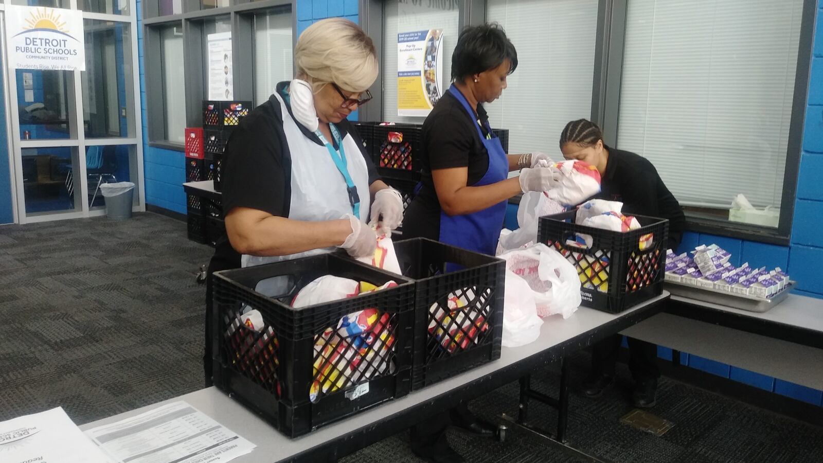 School staff pack up meals as part of a massive effort to feed families during Michigan’s statewide school shut down. Photo Credit: Eleanore Catolico/Chalkbeat