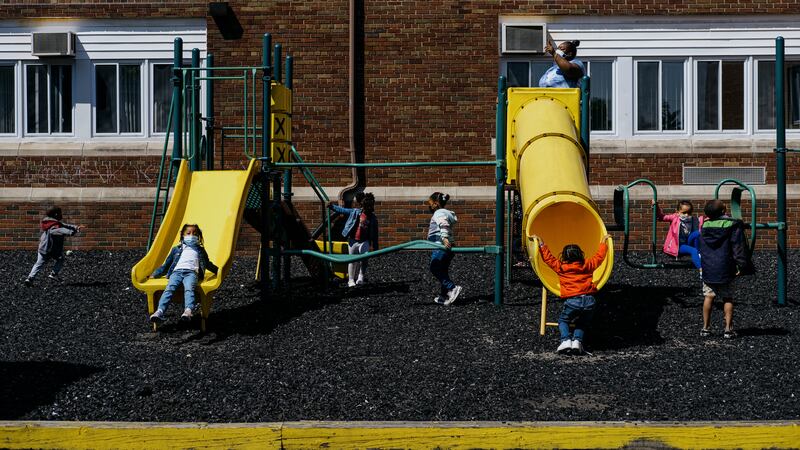 Children play on a yellow slide set on the side of a school building.