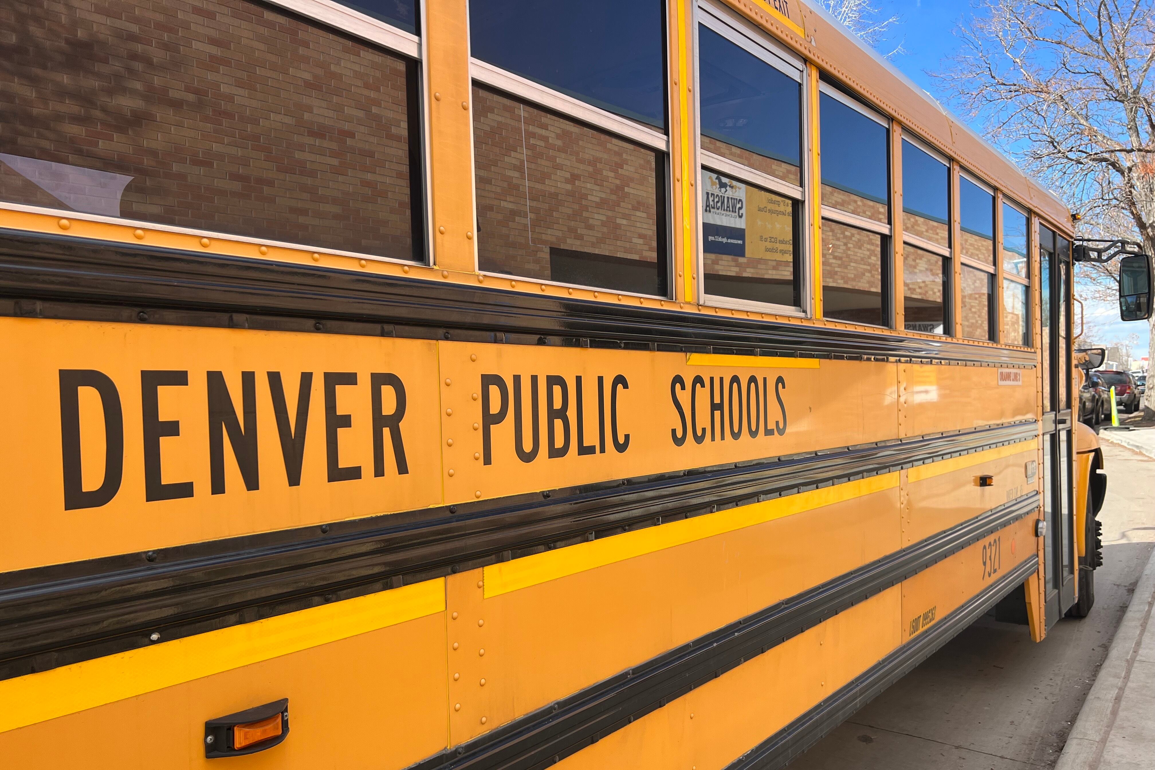 A Denver Public Schools school bus is parked with a little bit of a blue sky showing in the background.