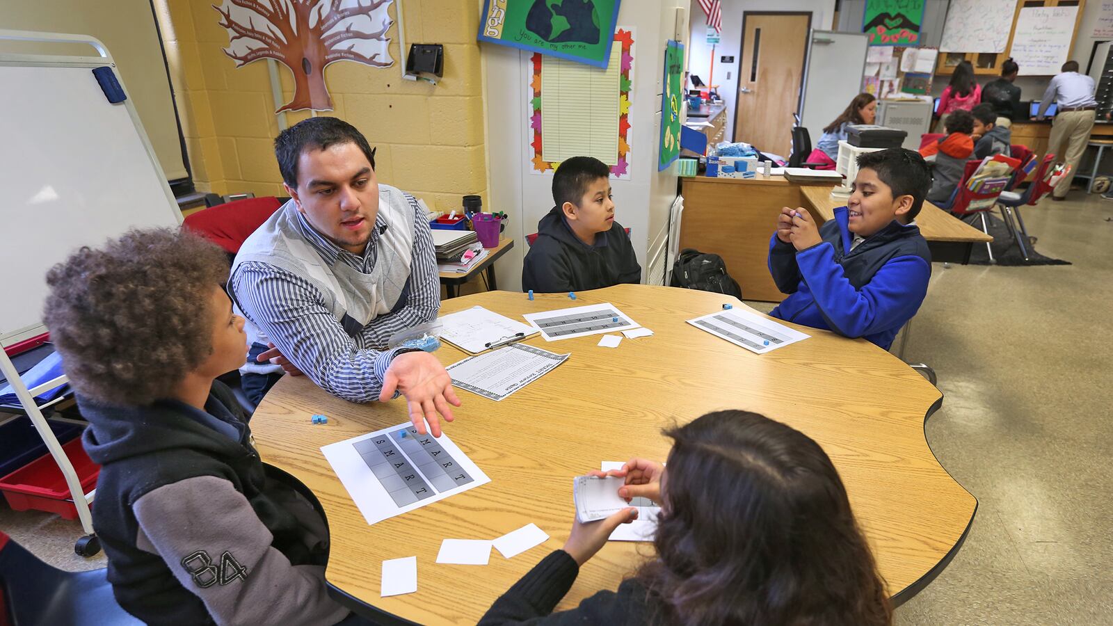 Fourth grade instructional aid Henry Velasquez works with students at Enlace Academy. More than half of the school's students are English learners.