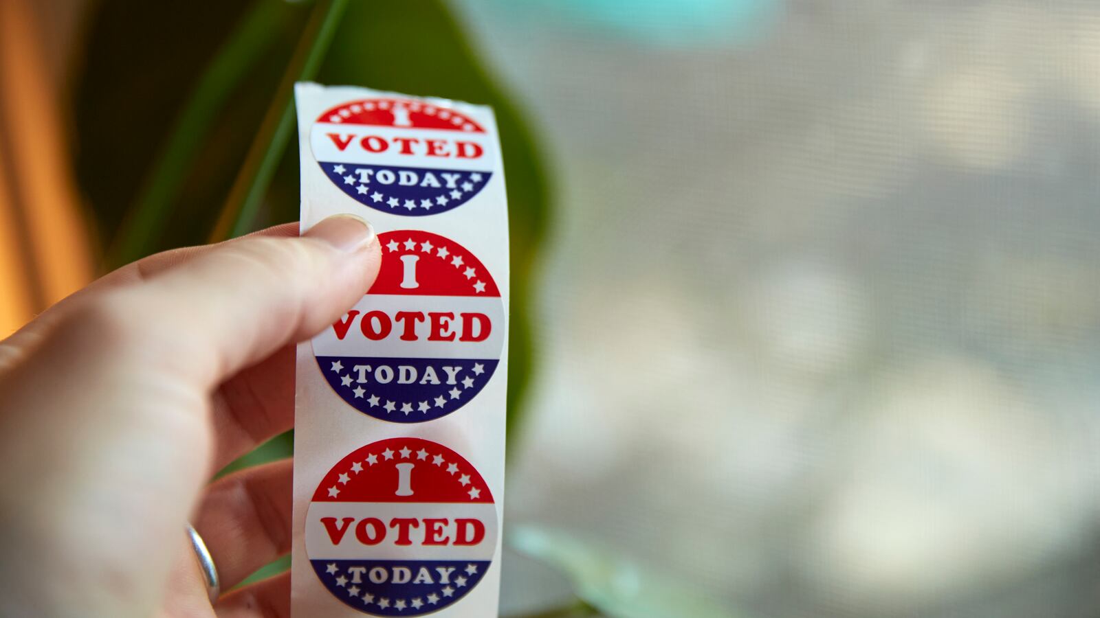 A hand holds a strip of “I Voted Today” stickers.