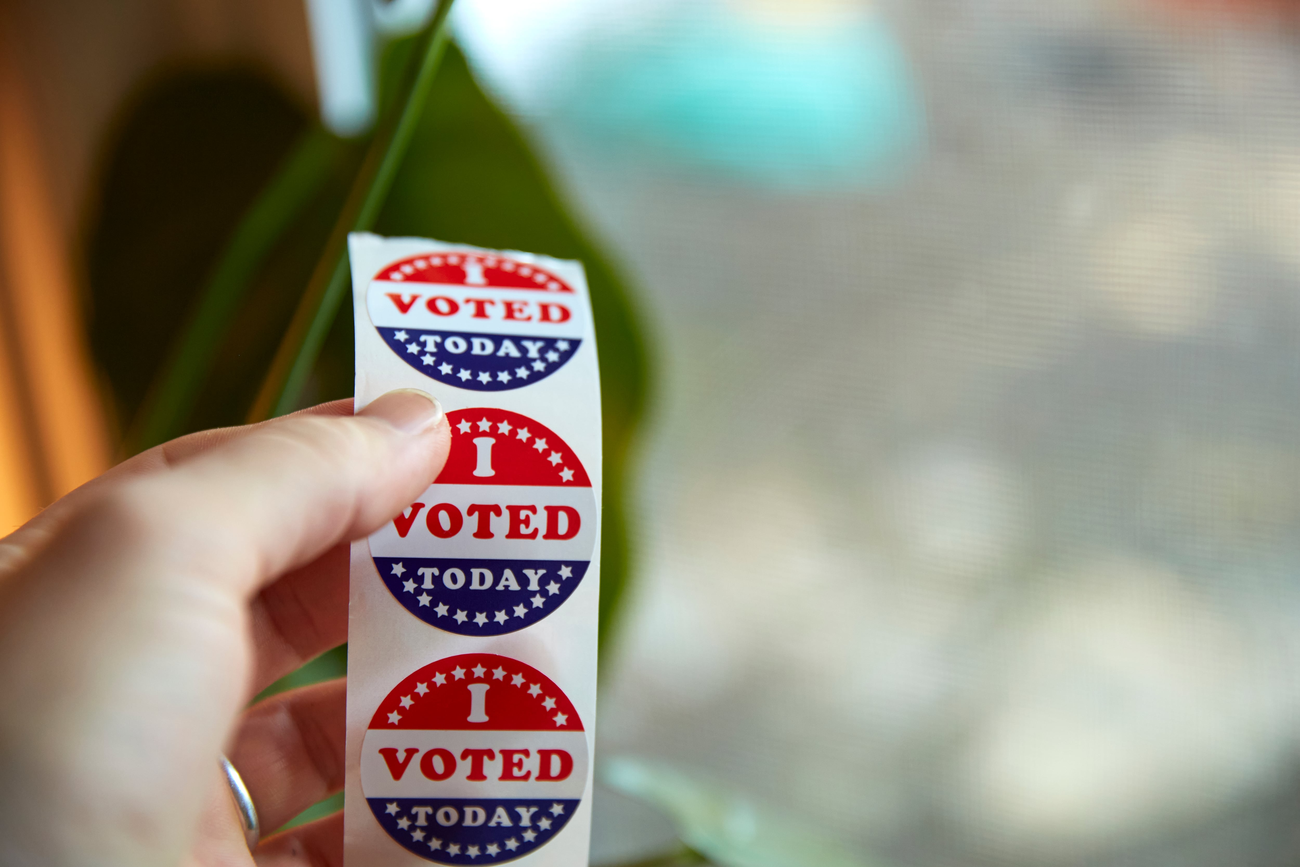 A hand holds a strip of “I Voted Today” stickers.