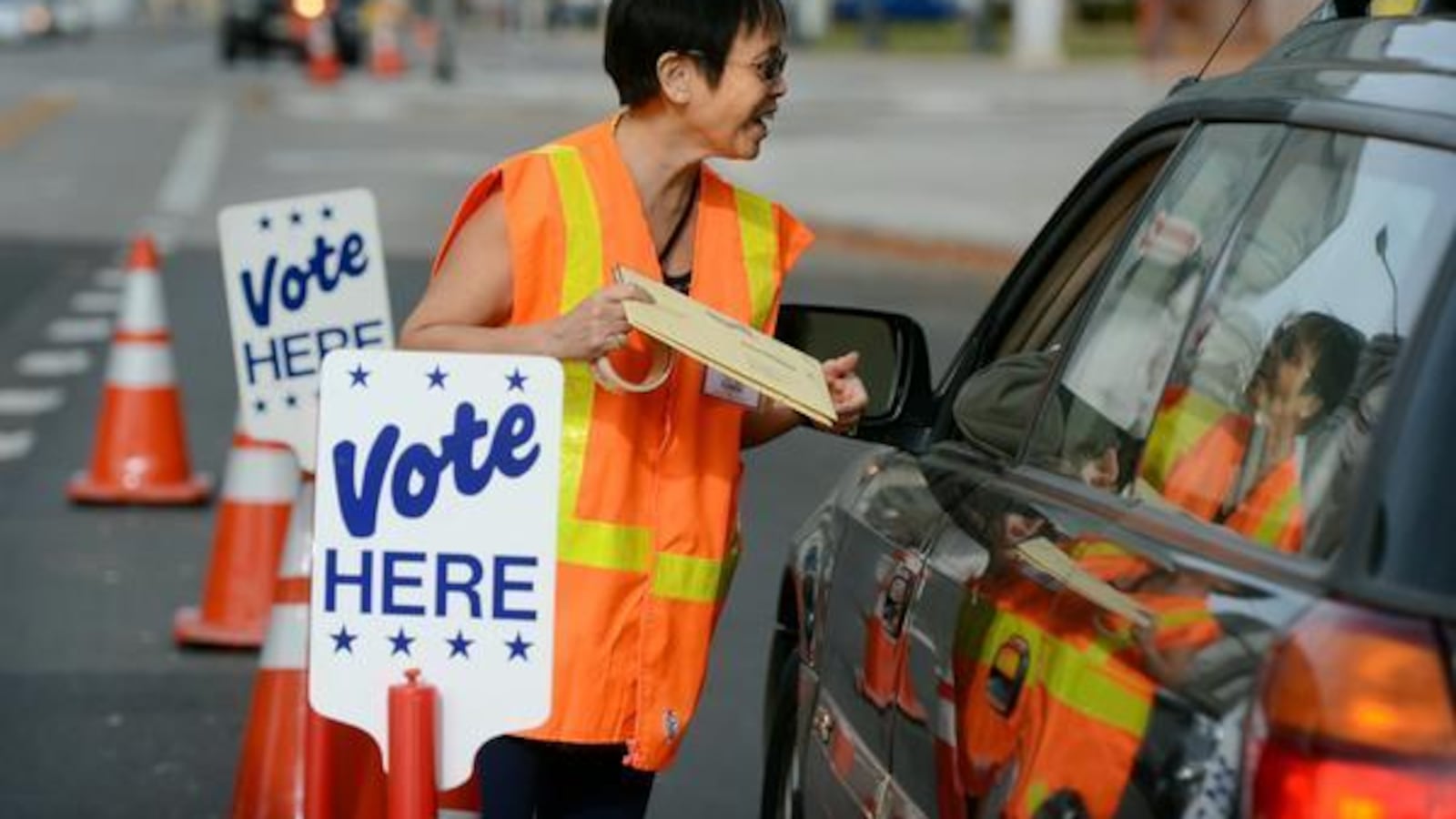 Election judge Josie Flanagan takes ballots from a voter at the drive-through ballot drop-off outside the Denver Elections Division.