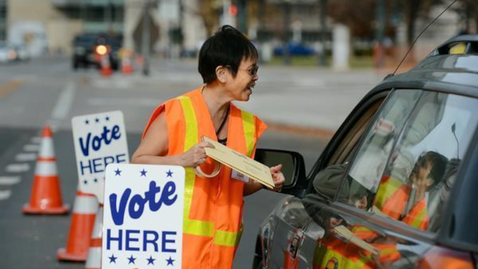 Election judge Josie Flanagan takes ballots from a voter at the drive-through ballot drop-off outside the Denver Elections Division.