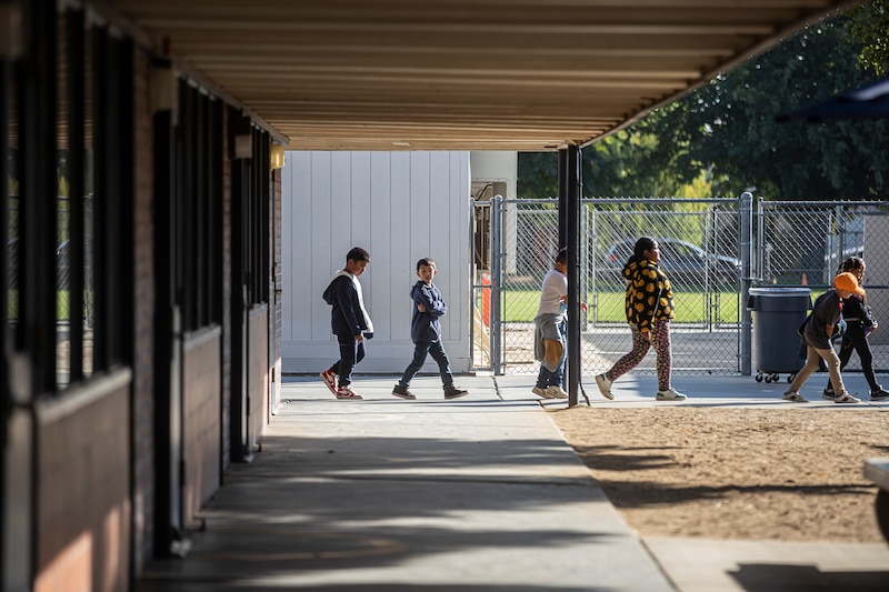 Students walk in a line on a campus.