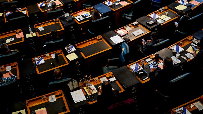 Colorado lawmakers sit at brown wood desks lined in rows in the state’s House of Representative chambers.