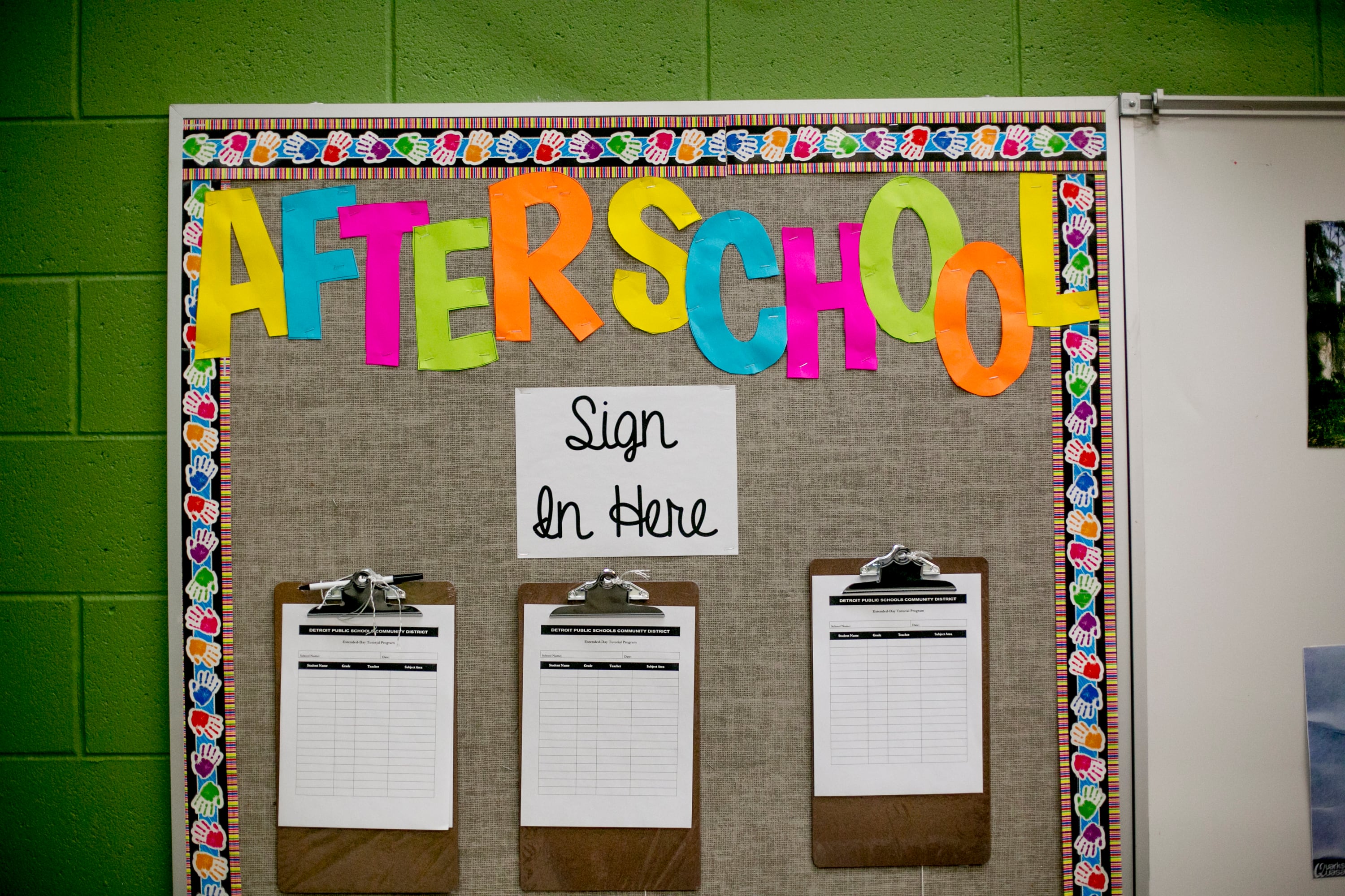 A photograph of a colorful sign that reads "After school" with sign up sheets in a school building hallway.