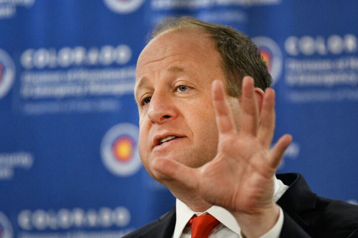 Governor Jared Polis gestures with his hand while speaking.
