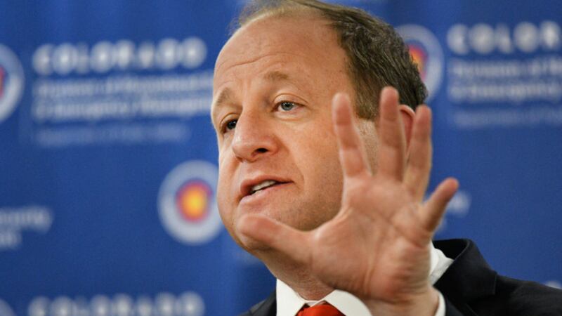 Governor Jared Polis gestures with his hand while speaking.