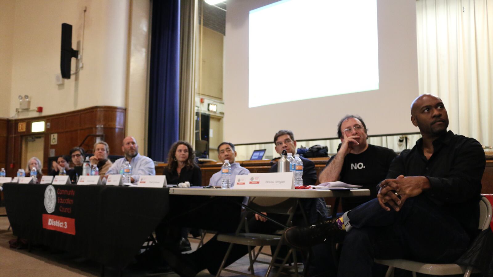 A line of people sit at a table.