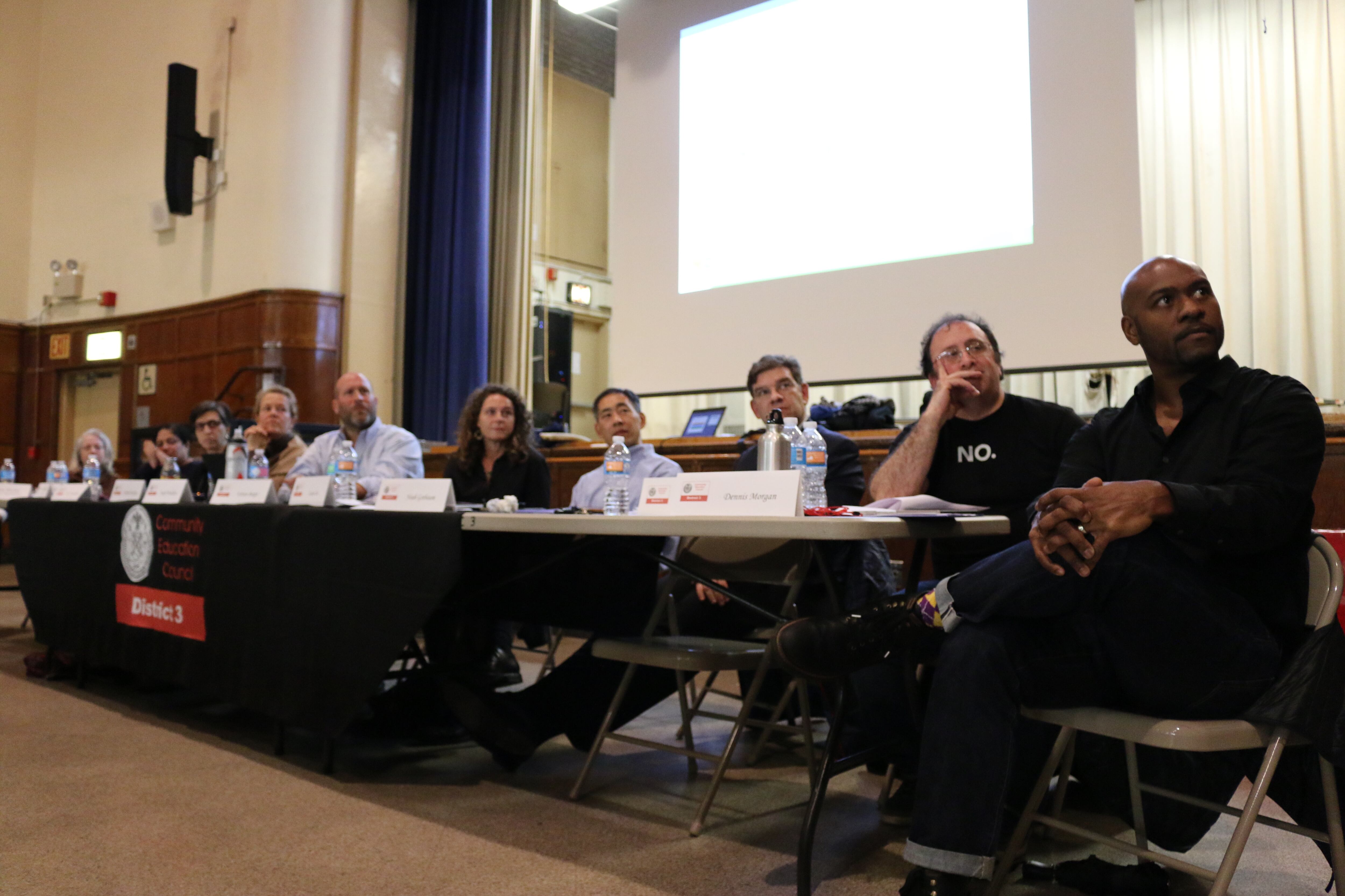 A line of people sit at a table.