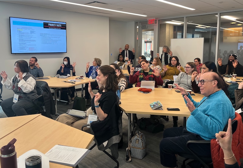 A photograph of adults and students sitting in a classroom.