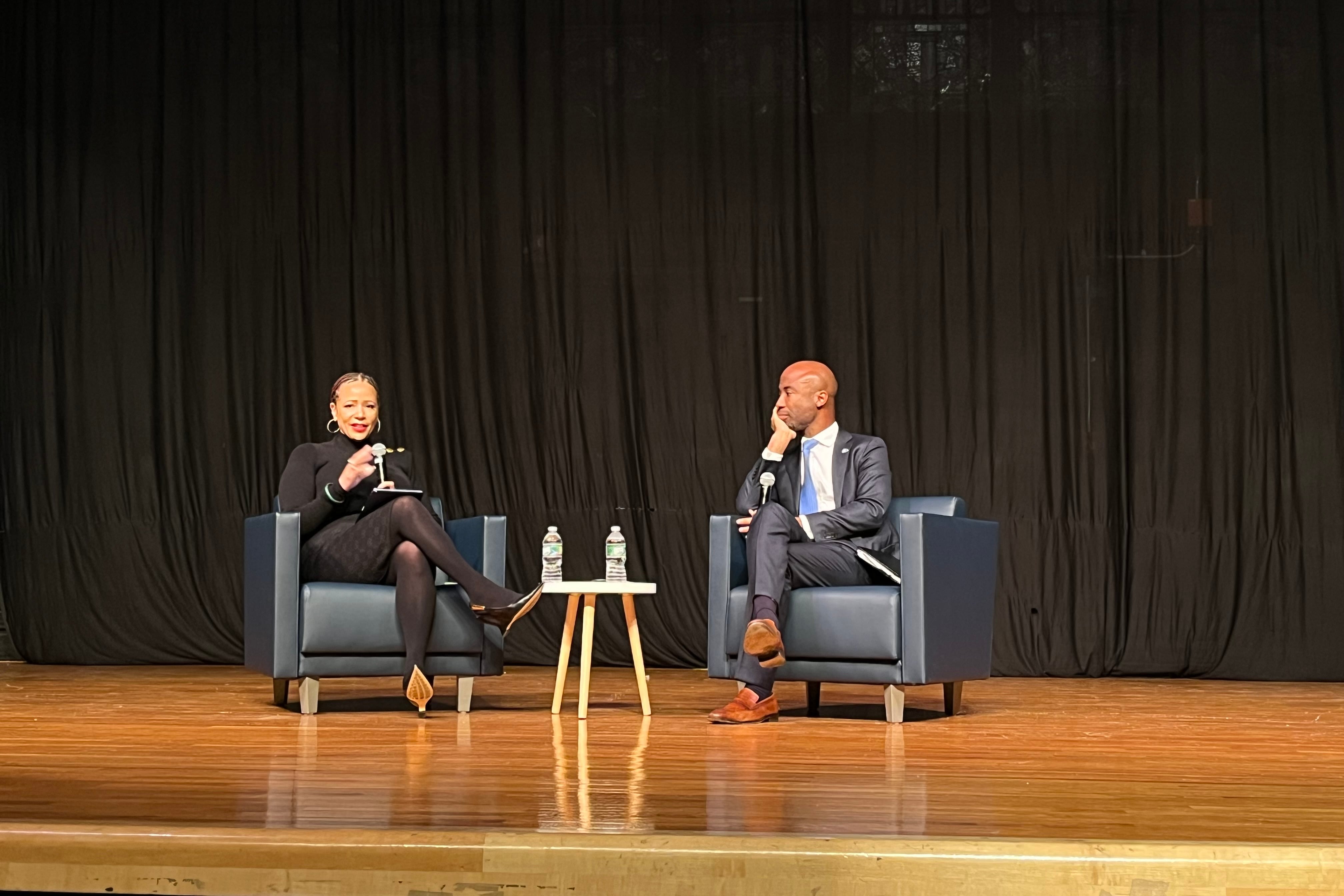 Two people sit on stage in conversation.