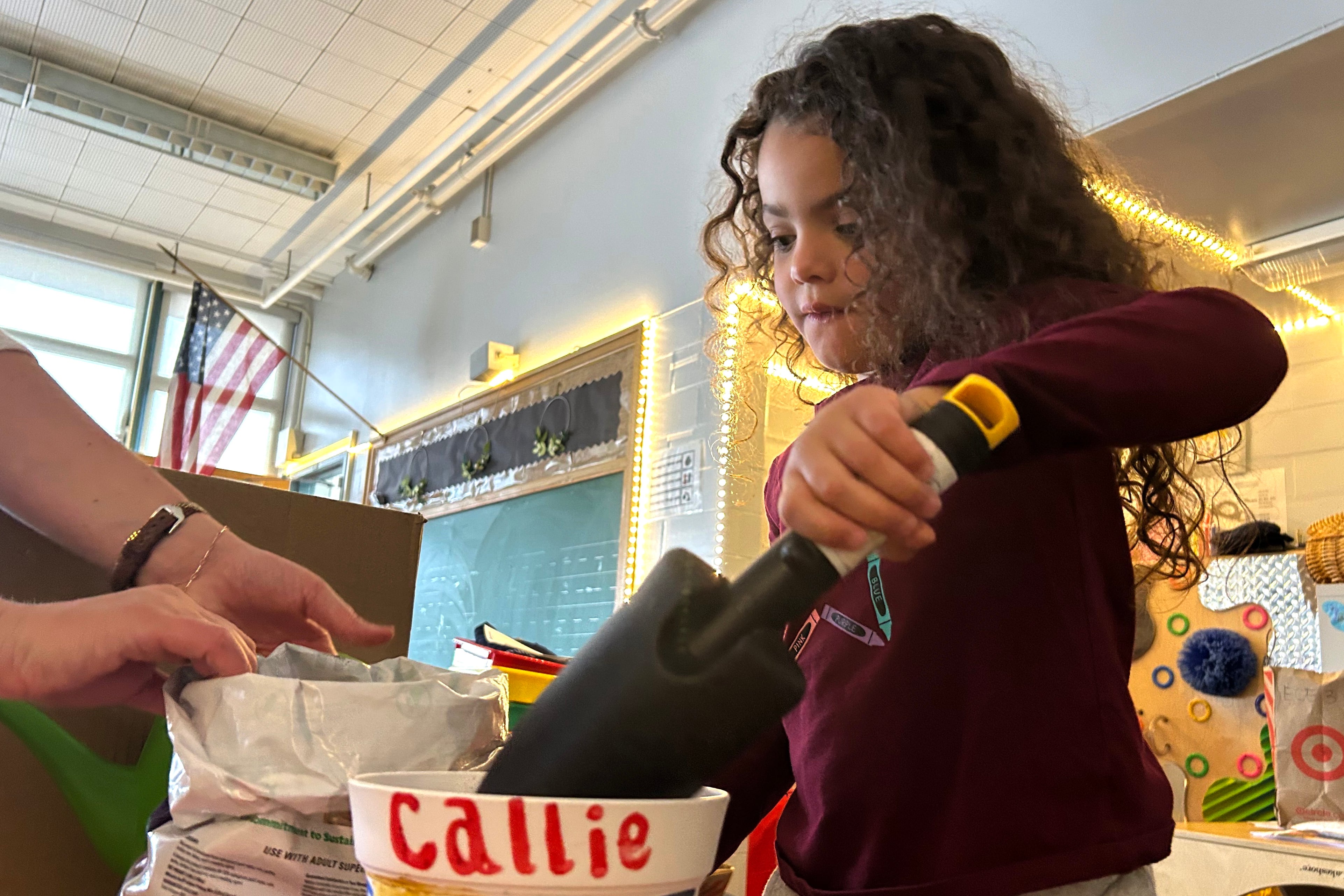 A young female student with long hair holds a small shovel.
