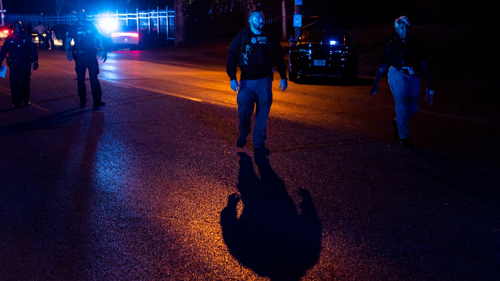 Police investigate a crime scene at night with police lights glowing