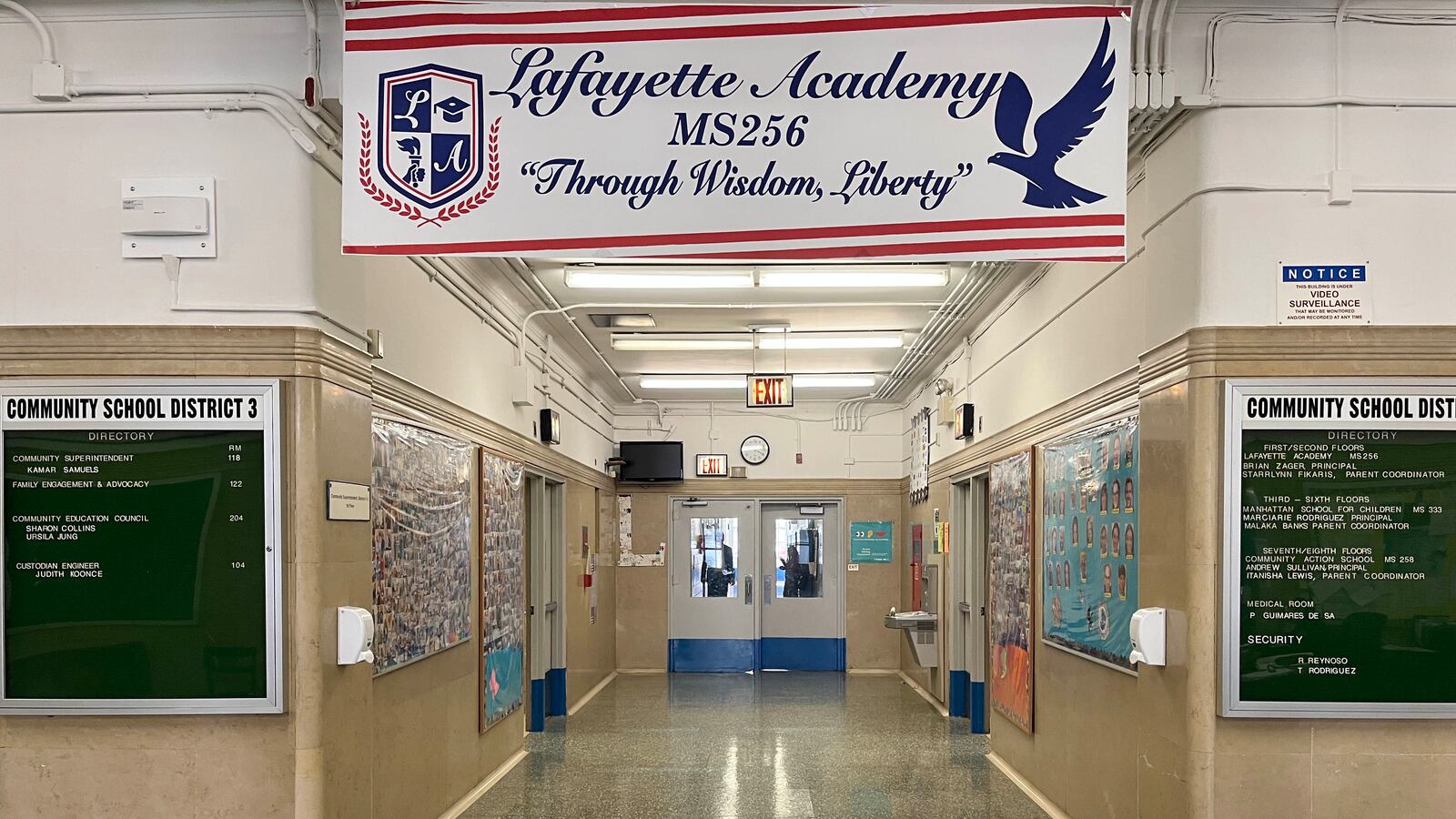A school hallway with a red and white banner with the school name on it and bulletin boards on both sides of the hallway.