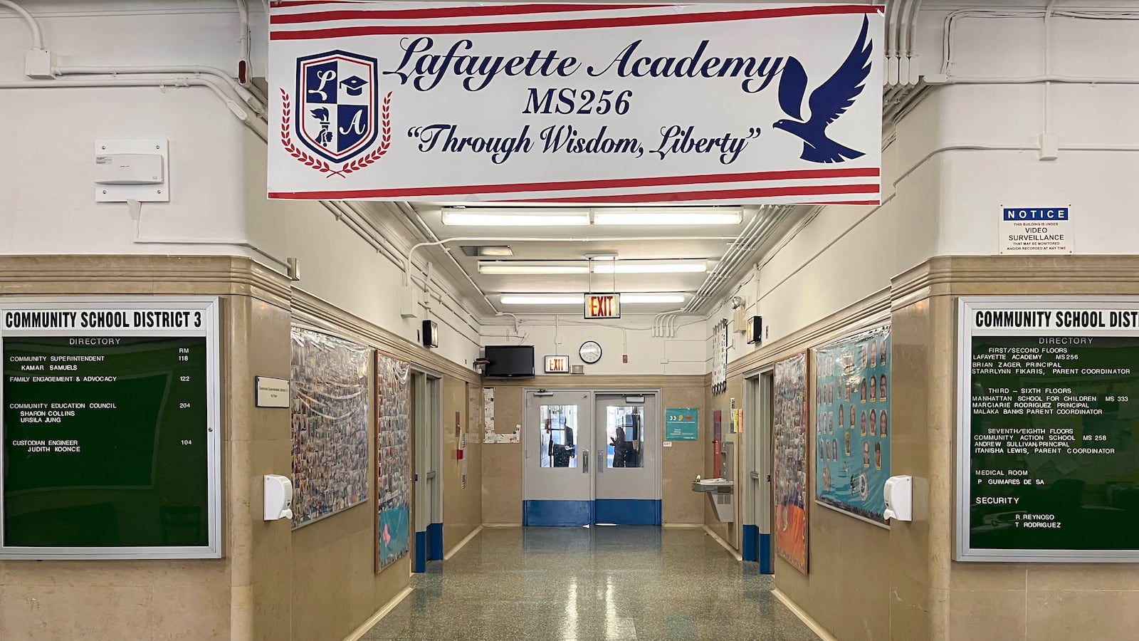 A school hallway with a red and white banner with the school name on it and bulletin boards on both sides of the hallway.
