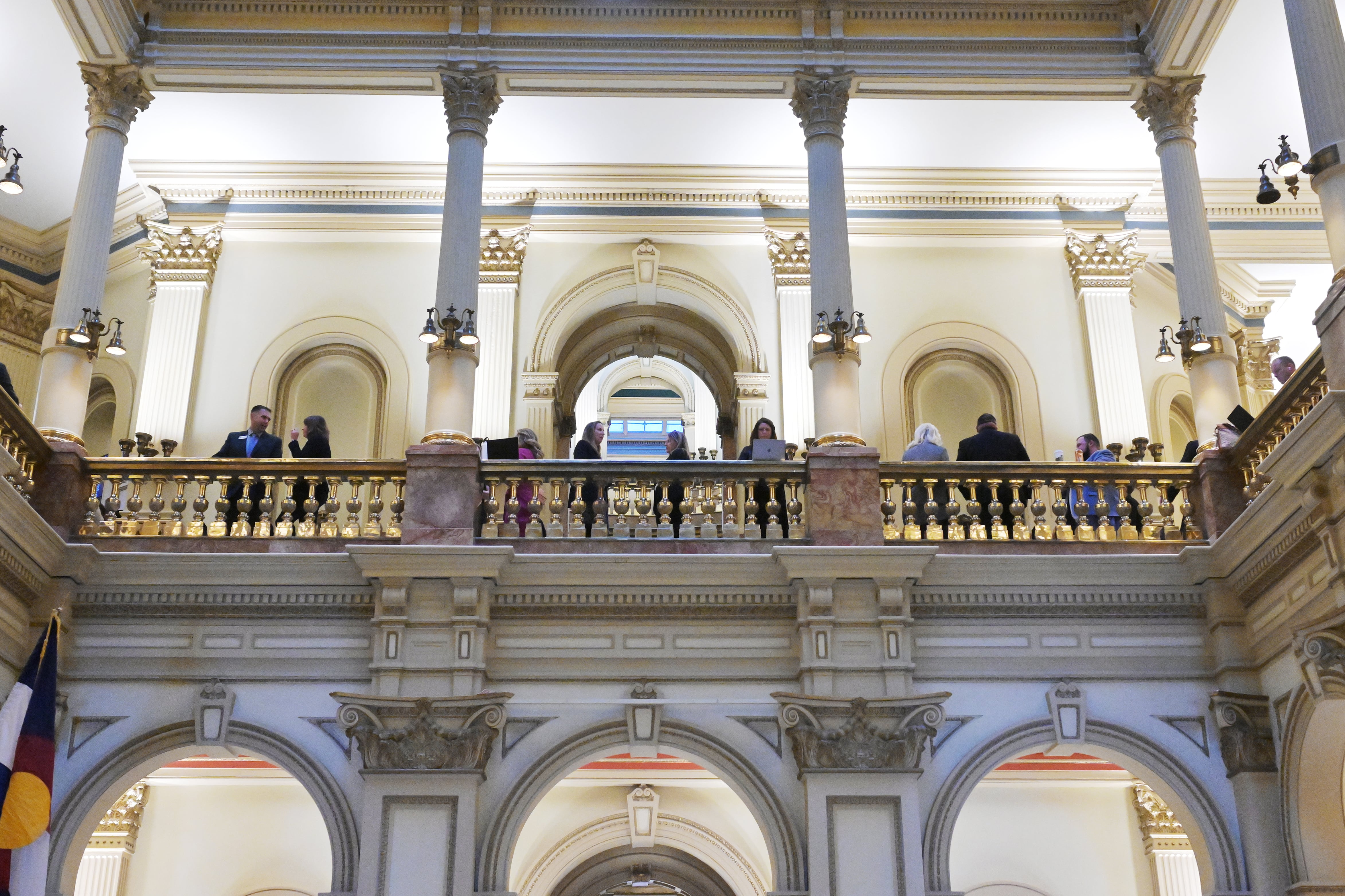 A group of people stand on the second floor of the Colorado State Capitol building.