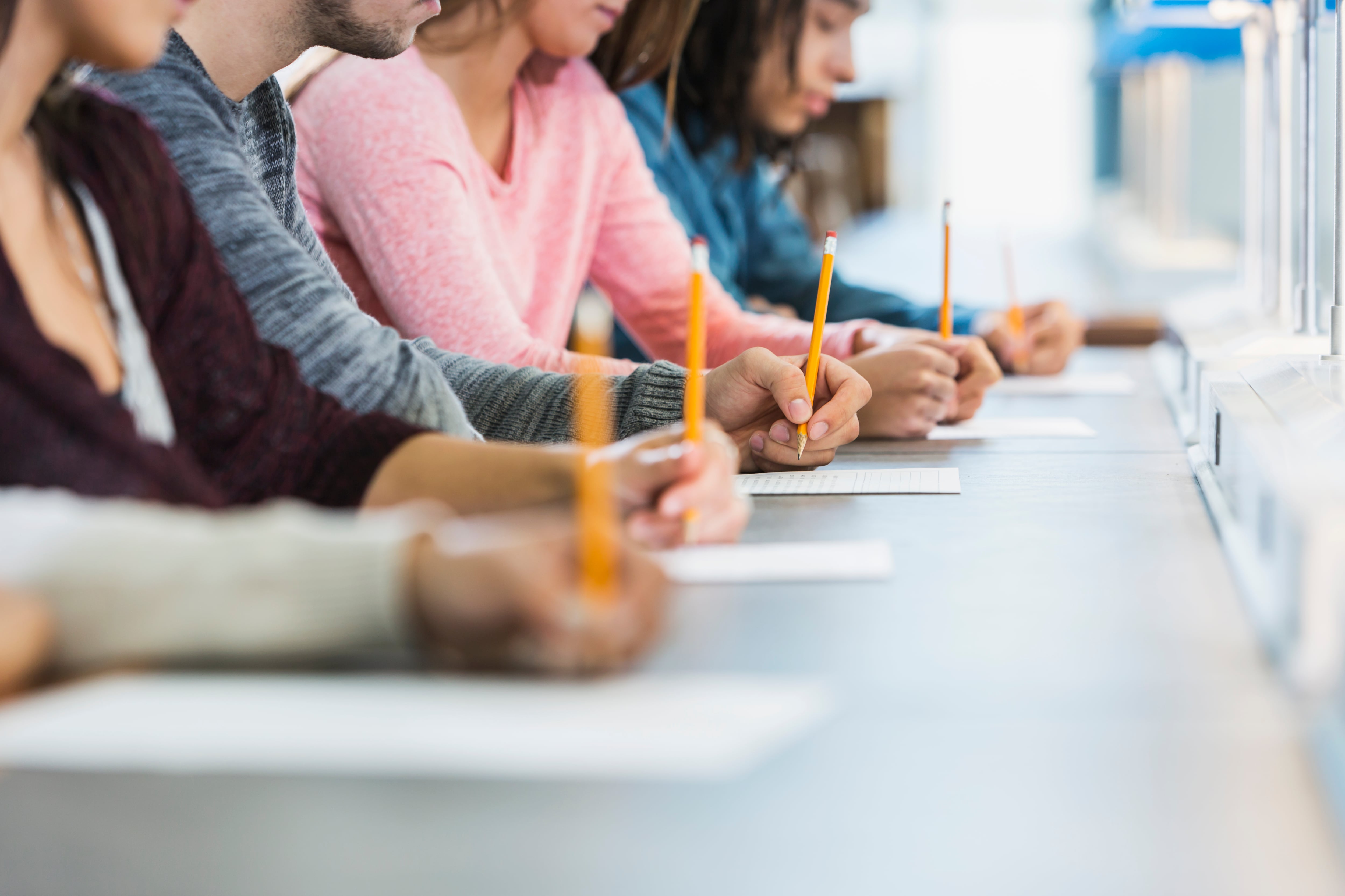 A group of students hold pencils at a table.