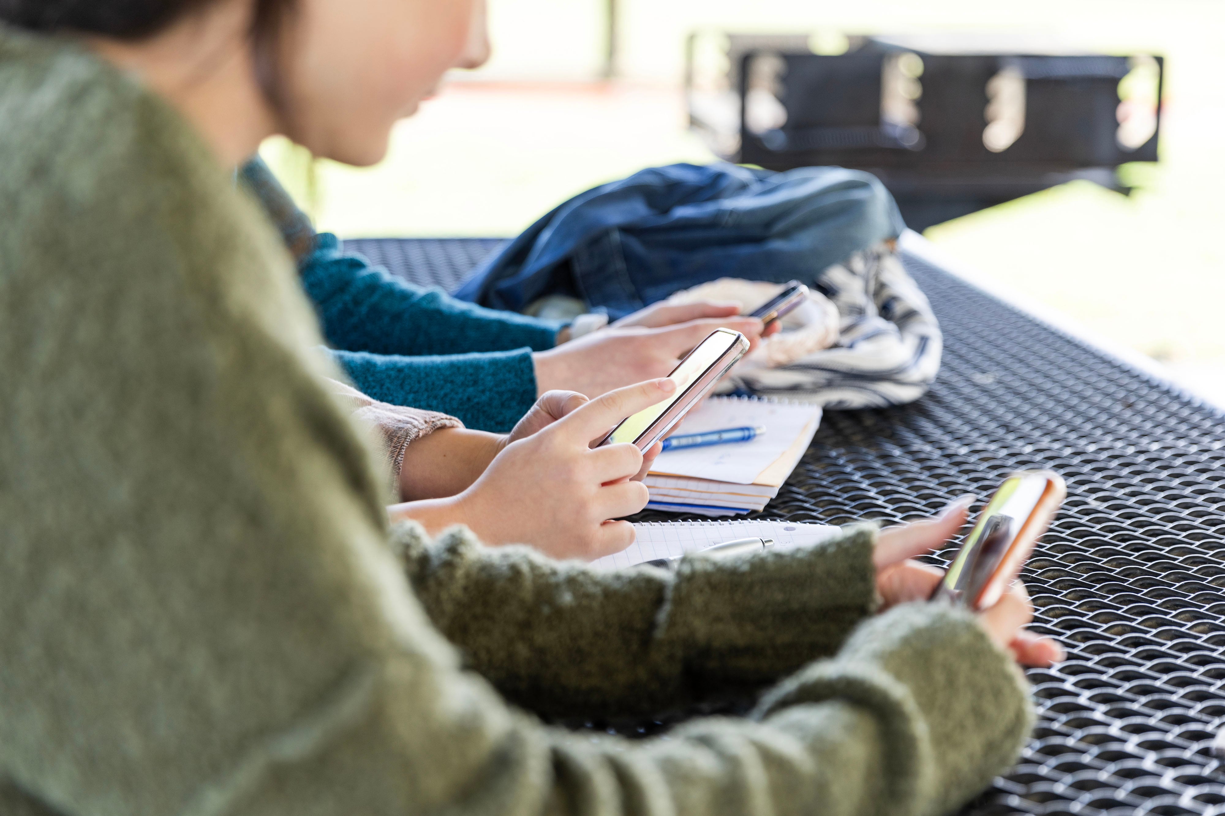 A close up of three students hands all holding cellphones.