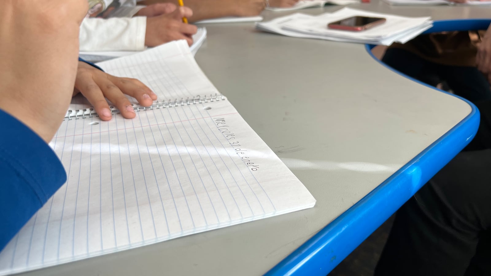 A photo of children in school writing in notebooks. Their notes are in Spanish.