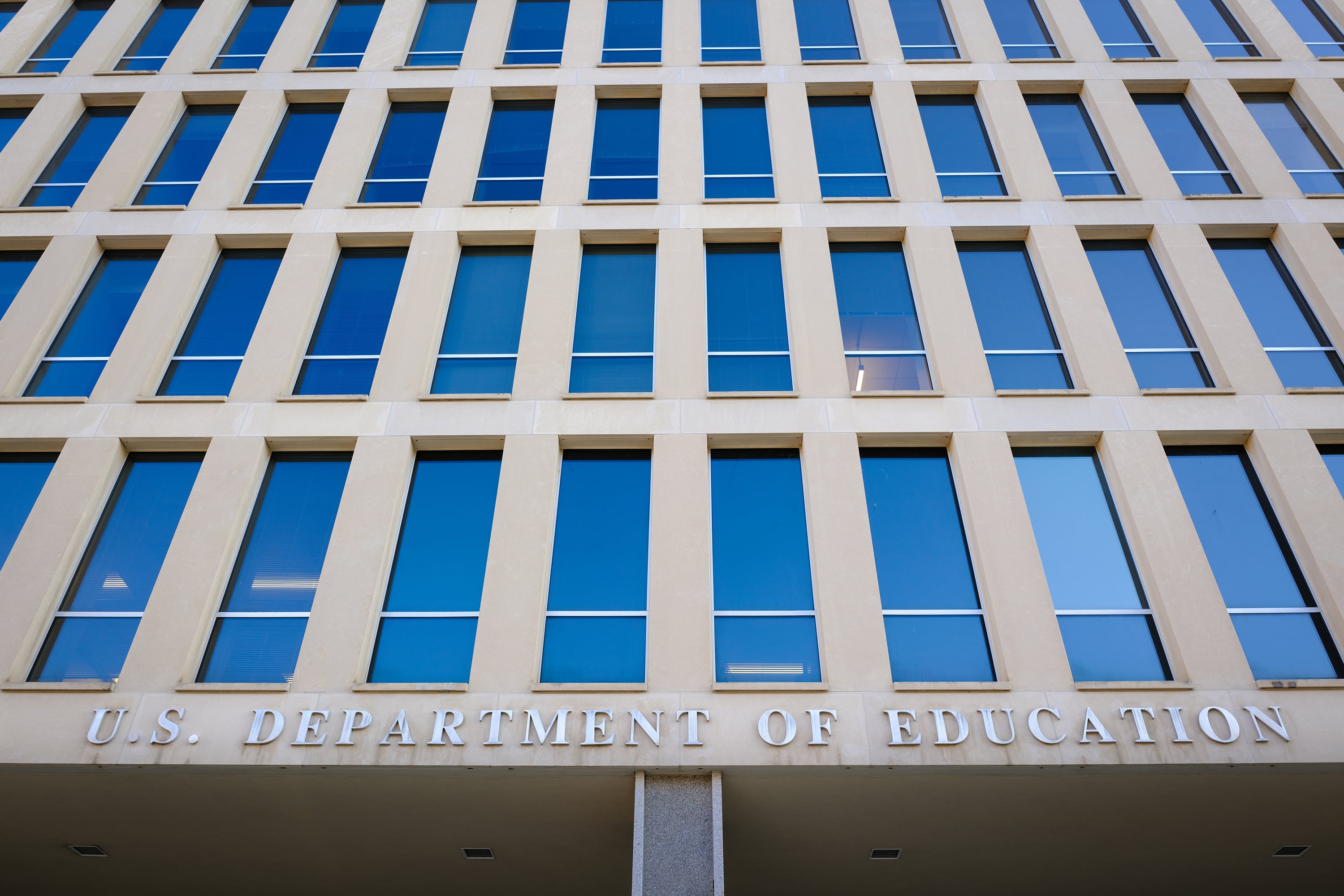 A close up photographer of the Department of Education Headquarters Building, showing four floors of floor to ceiling windows and the words "U.S. Department of Education" on the bottom.