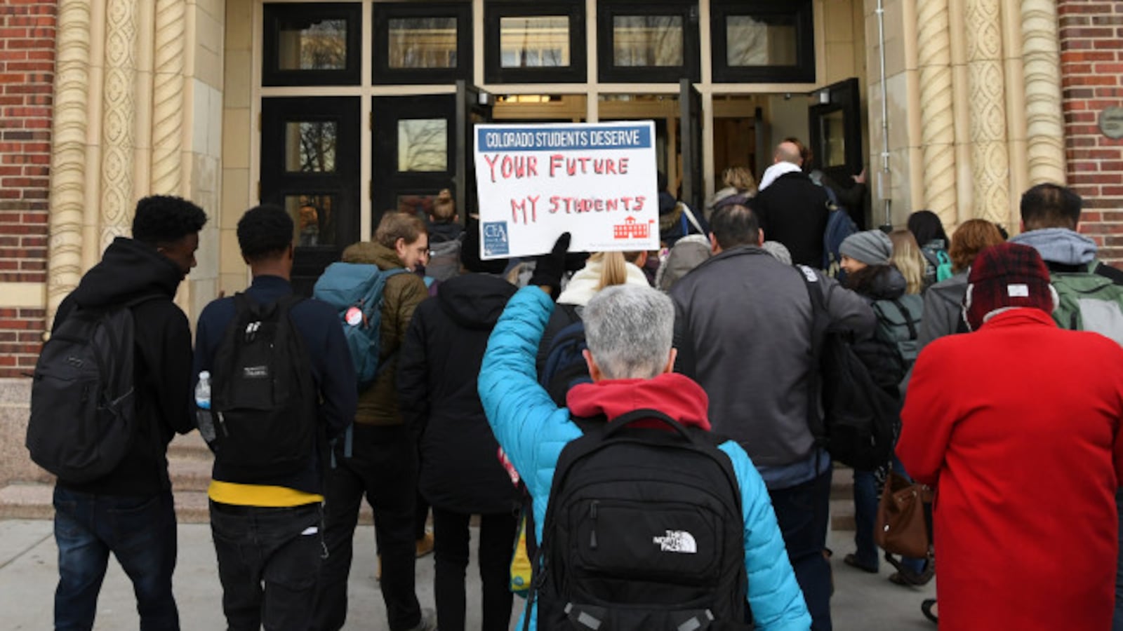 Special education teacher Bernie Janelle holds a sign as she walks into Denver's South High School.