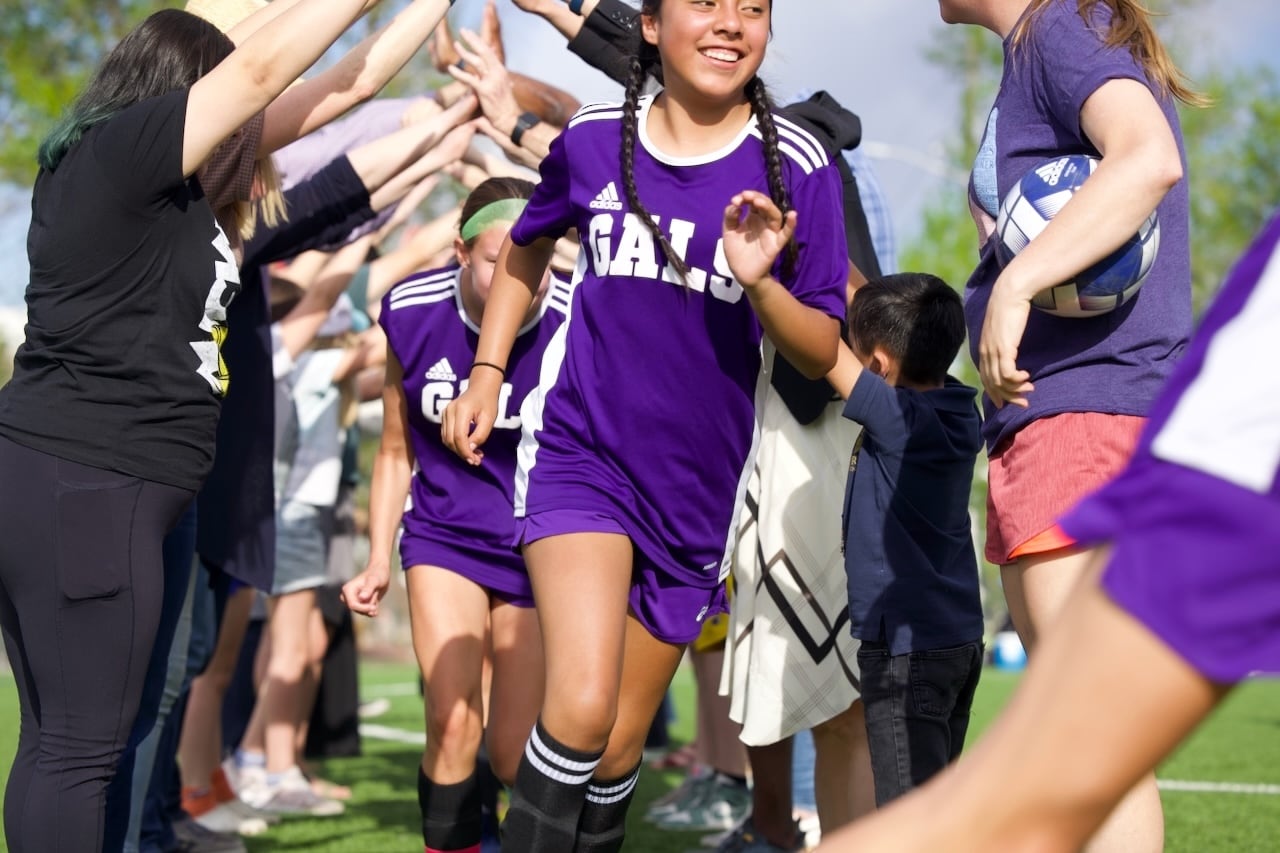 Girls in soccer uniforms run
