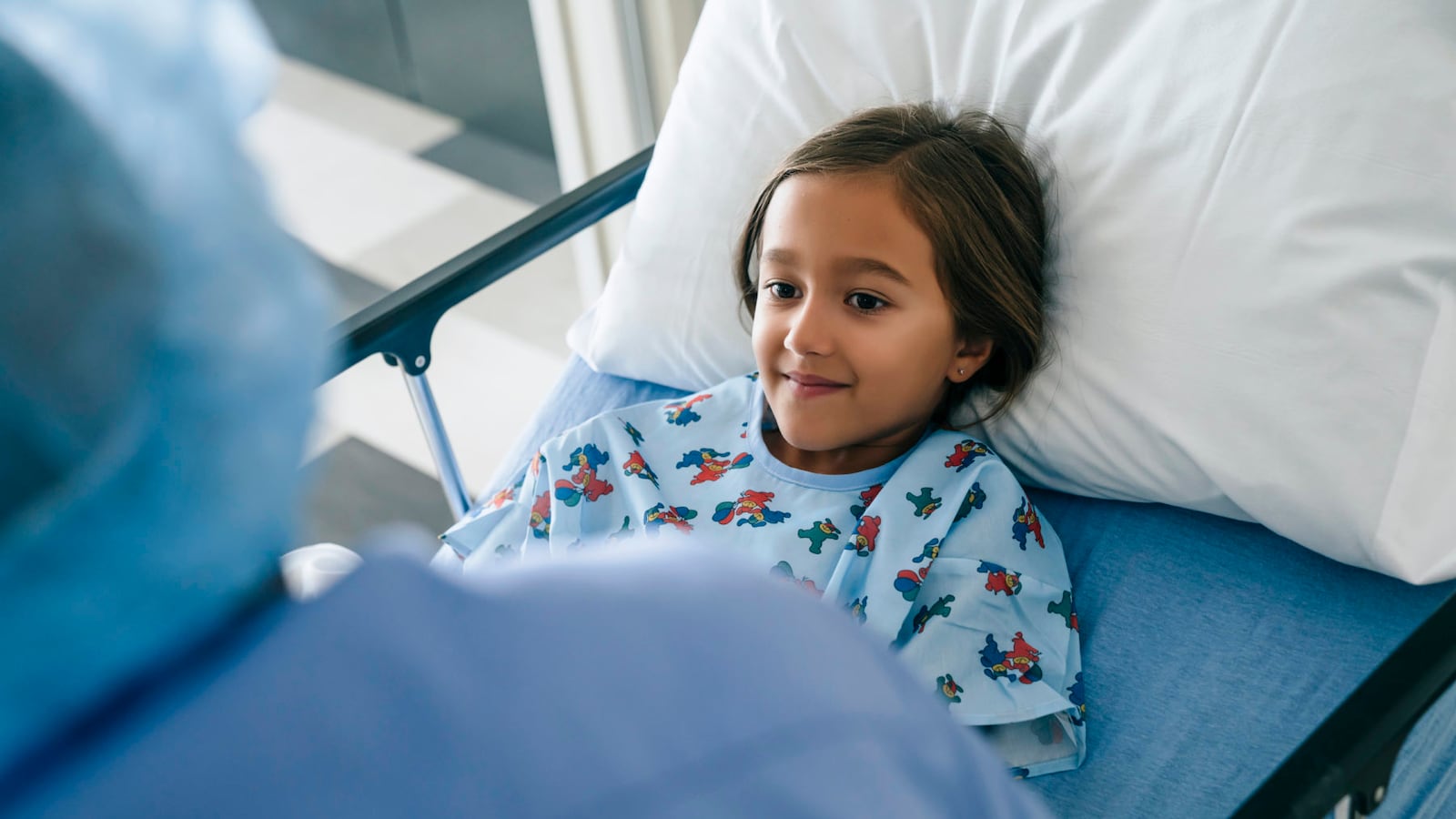 Nurse talking to girl in hospital bed