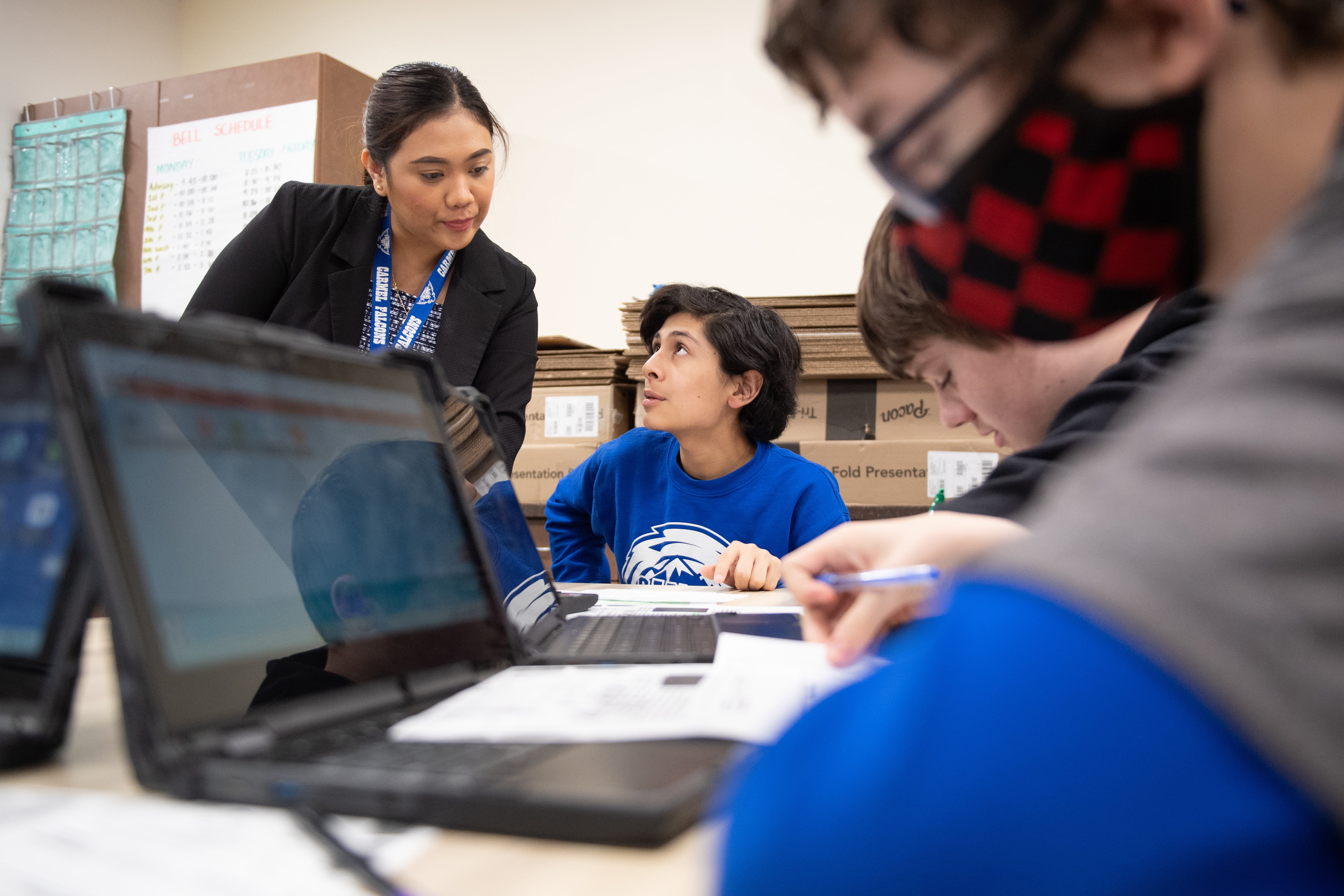 A woman with dark hair works with a student who is looking up at her.