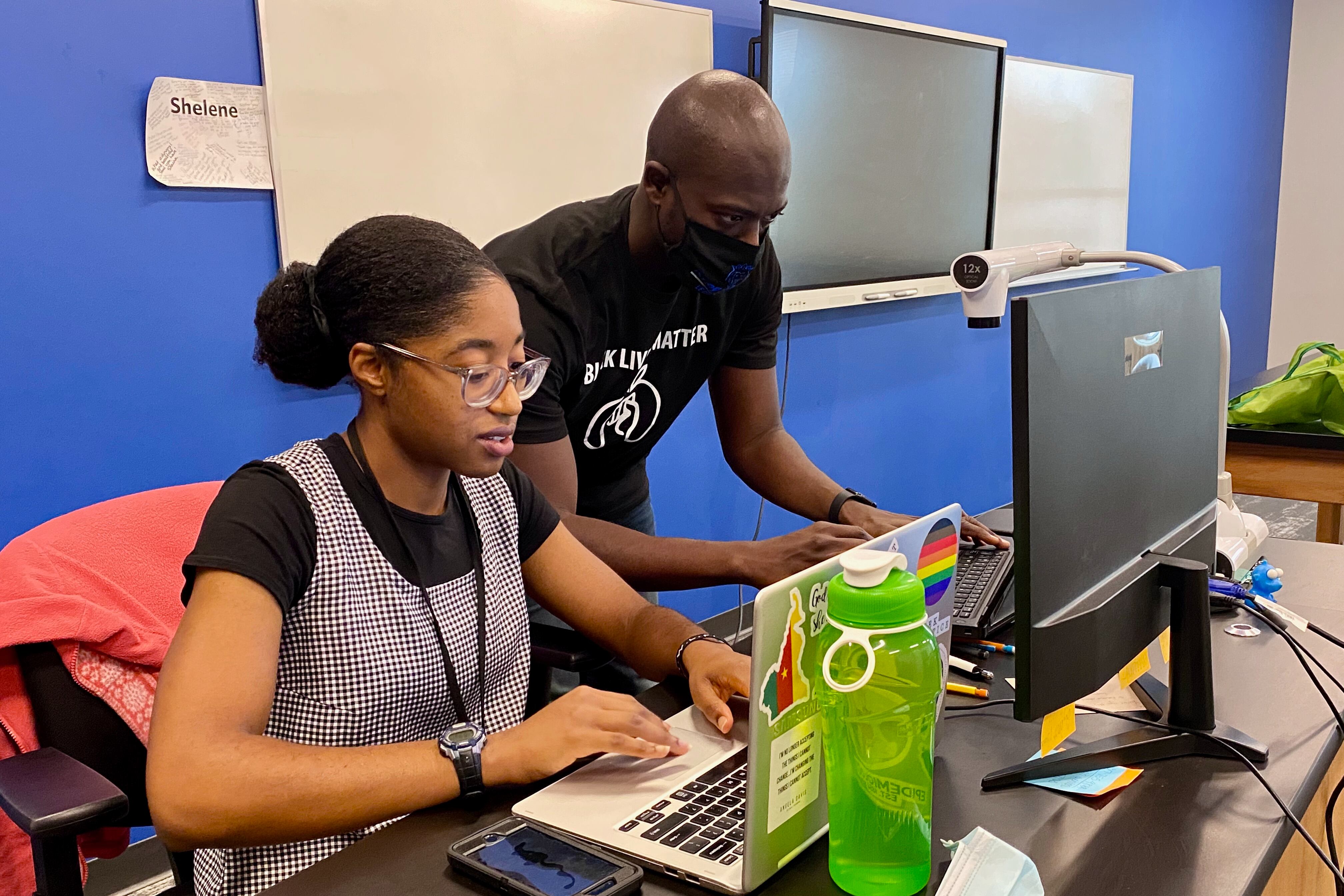 Shelene Baiyee teaches a remote lesson and David Spencer sets up at computer at KIPP Indy Legacy High School.