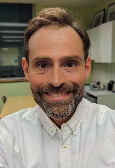 Headshot of a man with light brown hair wearing a white button-down shirt.