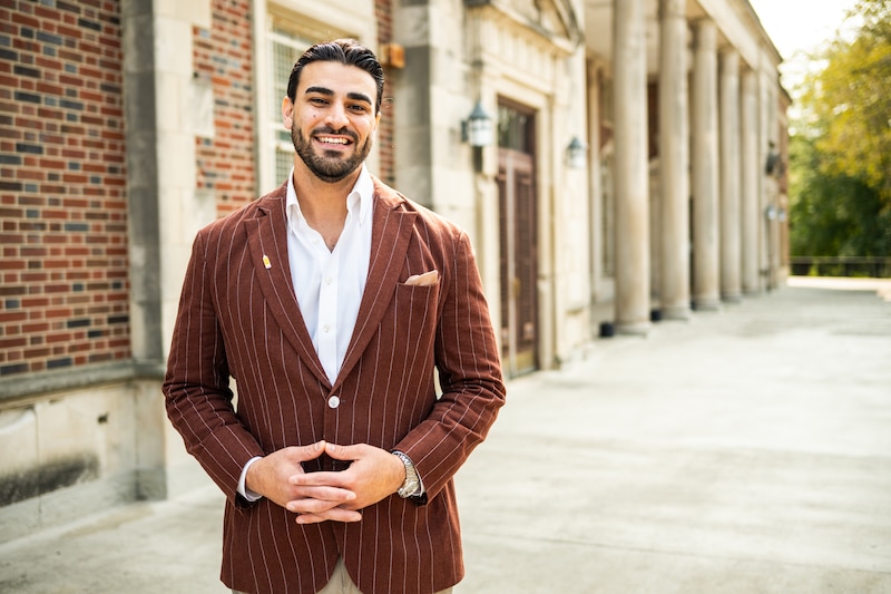 A man in a brown jacket and white shirt.