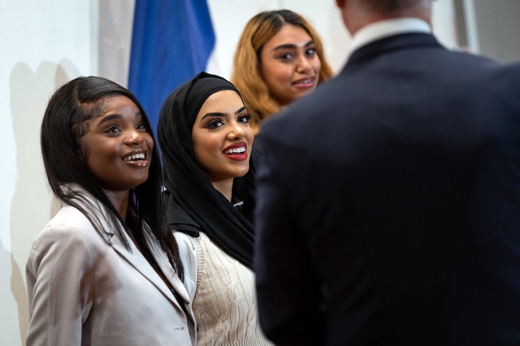 Three women stand in a group meeting others
