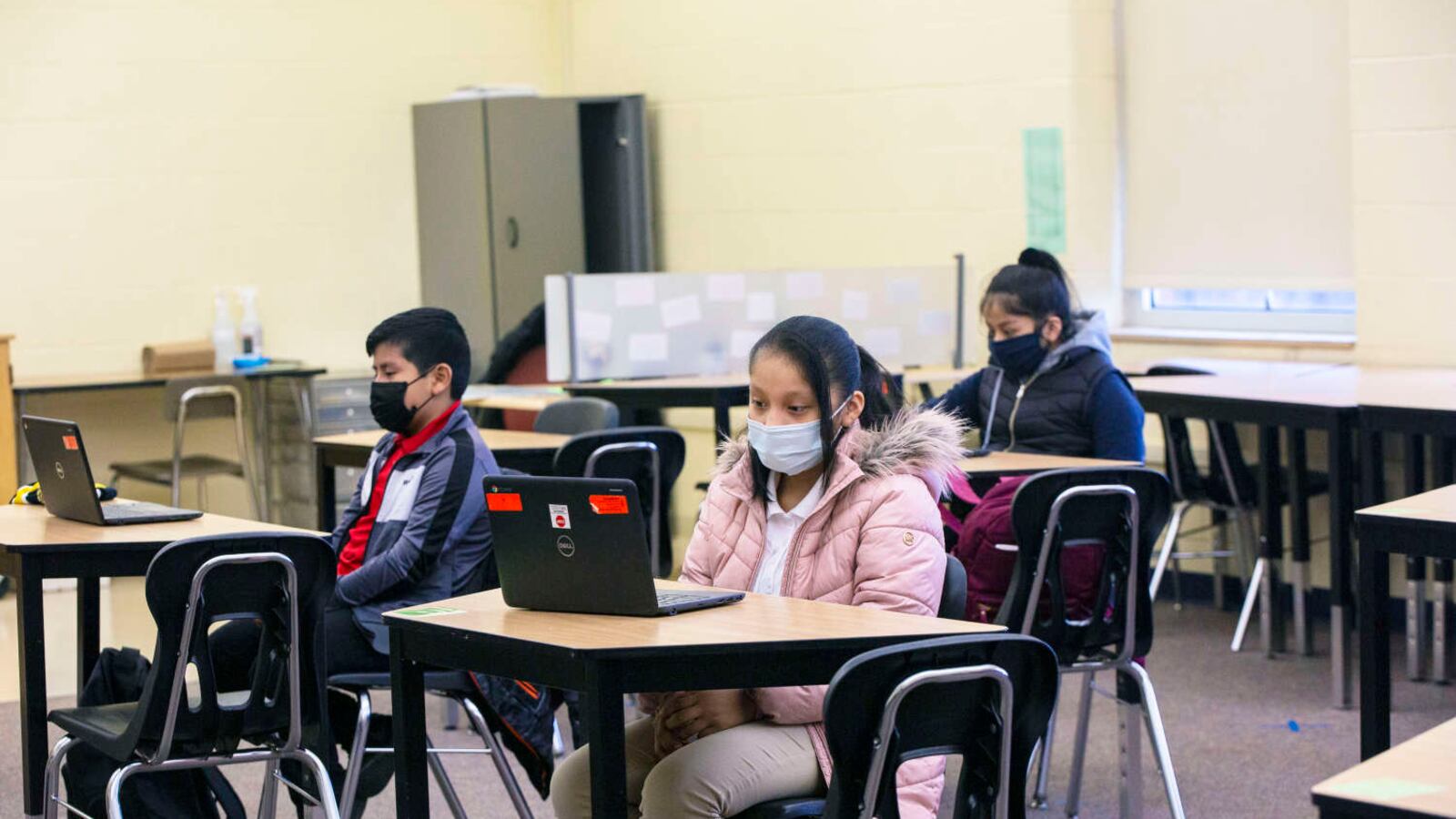 Students sit at desks, masked and distanced, on first day of in person learning