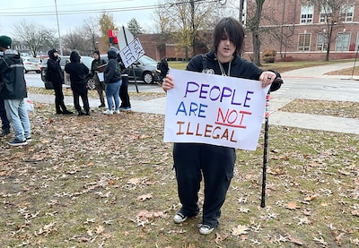A male student holds a sign near other people.