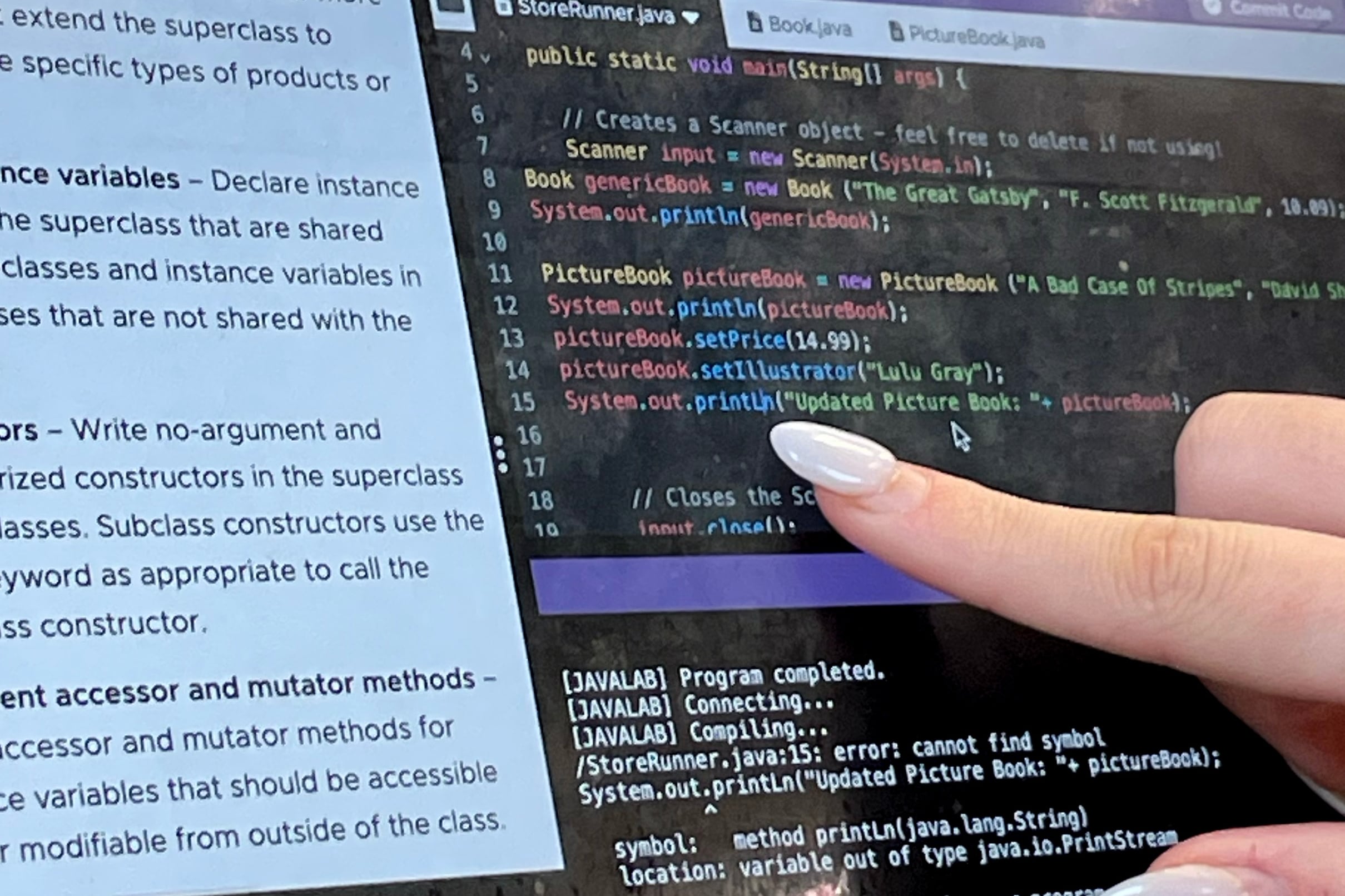 A hand pointing to a screen on a computer.