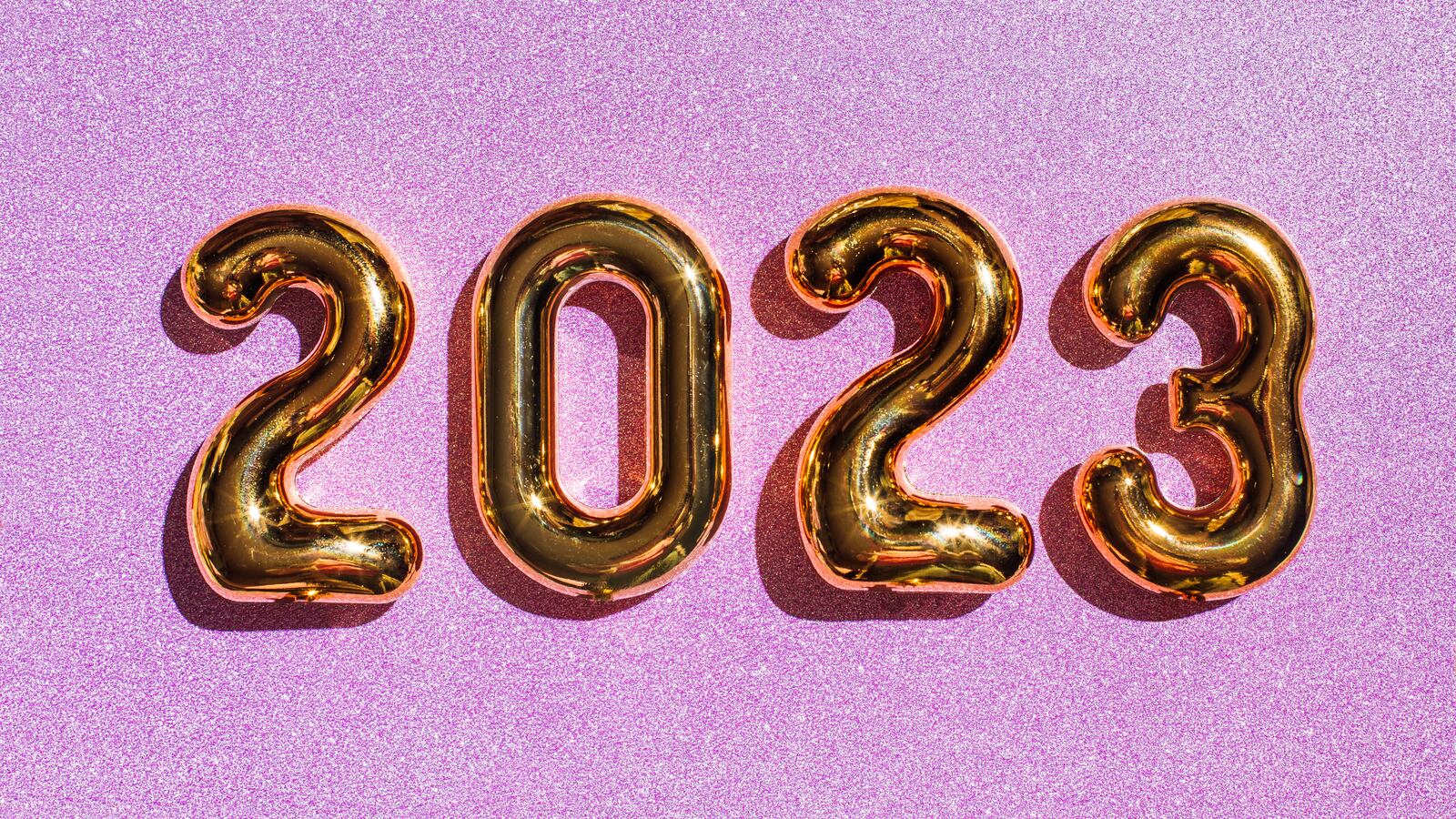 Numbered gold balloons showing 2023 on a pink glittery background.
