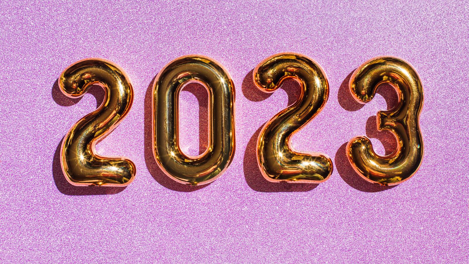 Numbered gold balloons showing 2023 on a pink glittery background.
