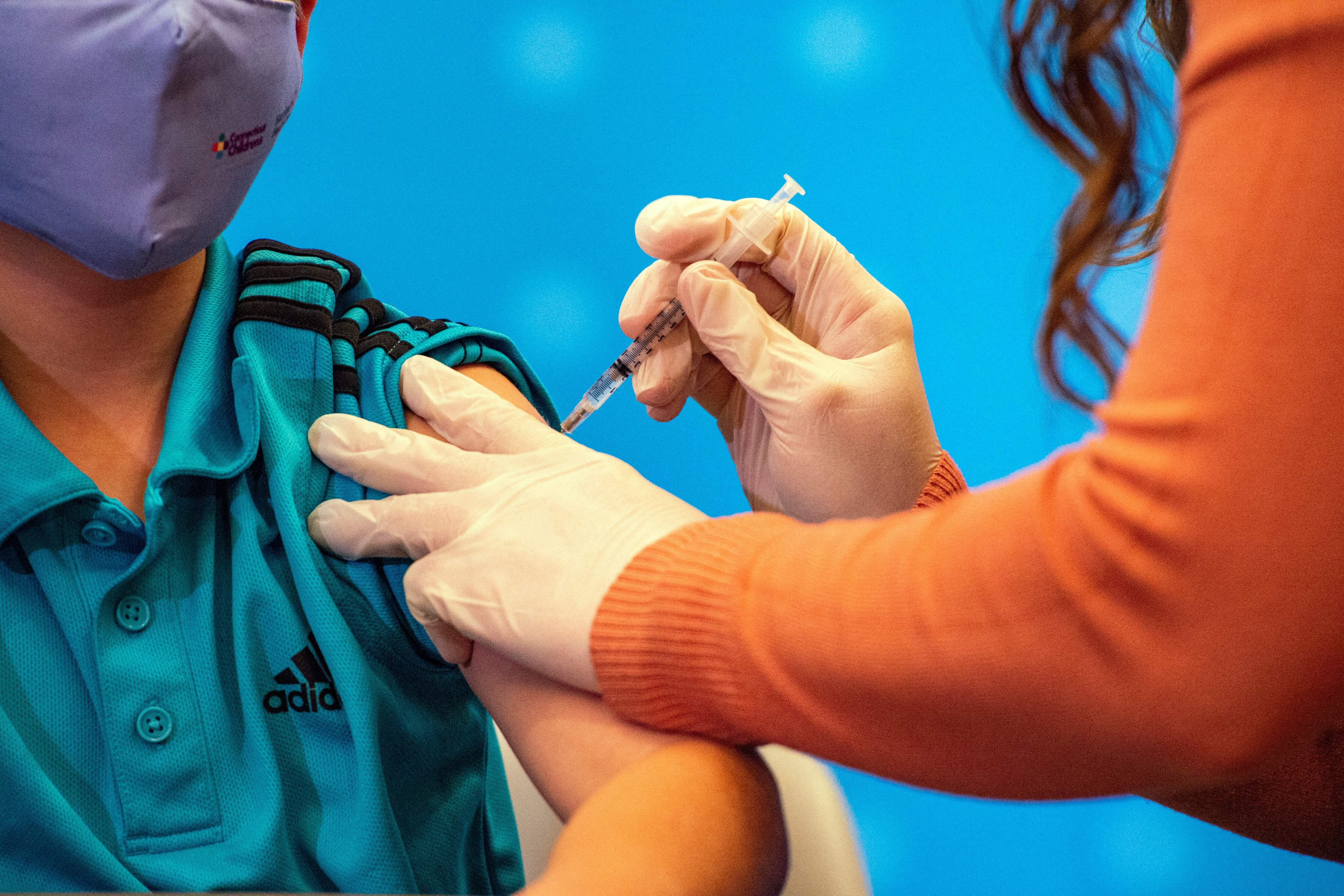 A woman healthcare worker gives a dose of the COVID vaccine to a young boy. New York City elementary schools will offer shots to children ages 5-11 next week.