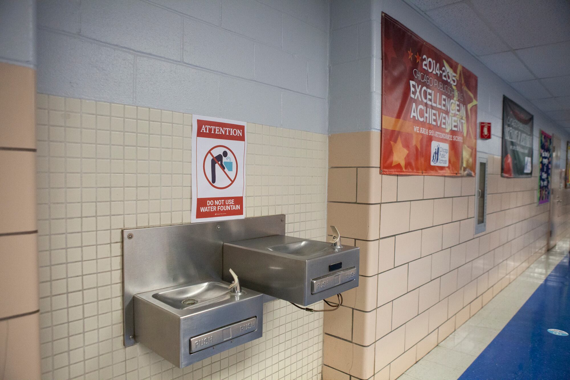 A sign between two water fountains that reads: Attention. Do not use water fountain.