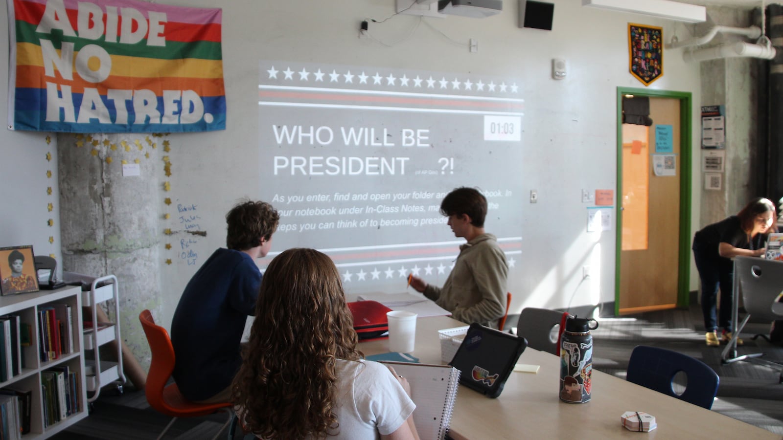 Three high school students work in a classroom.