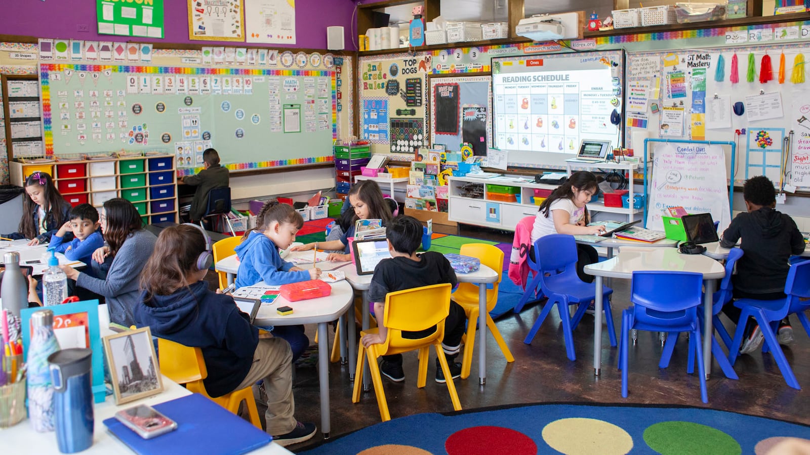 Students at CICS West Belden school work in the classroom. They sitting on brightly colored chairs around tables at the Chicago charter school. The walls are decorated with posters.