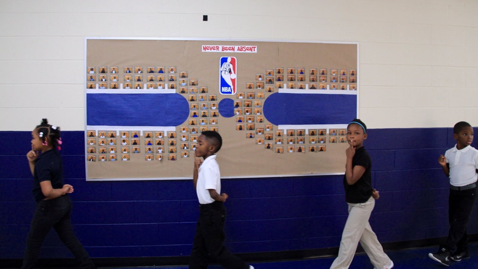 Students walk past a bulletin board celebrating students with best attendance.