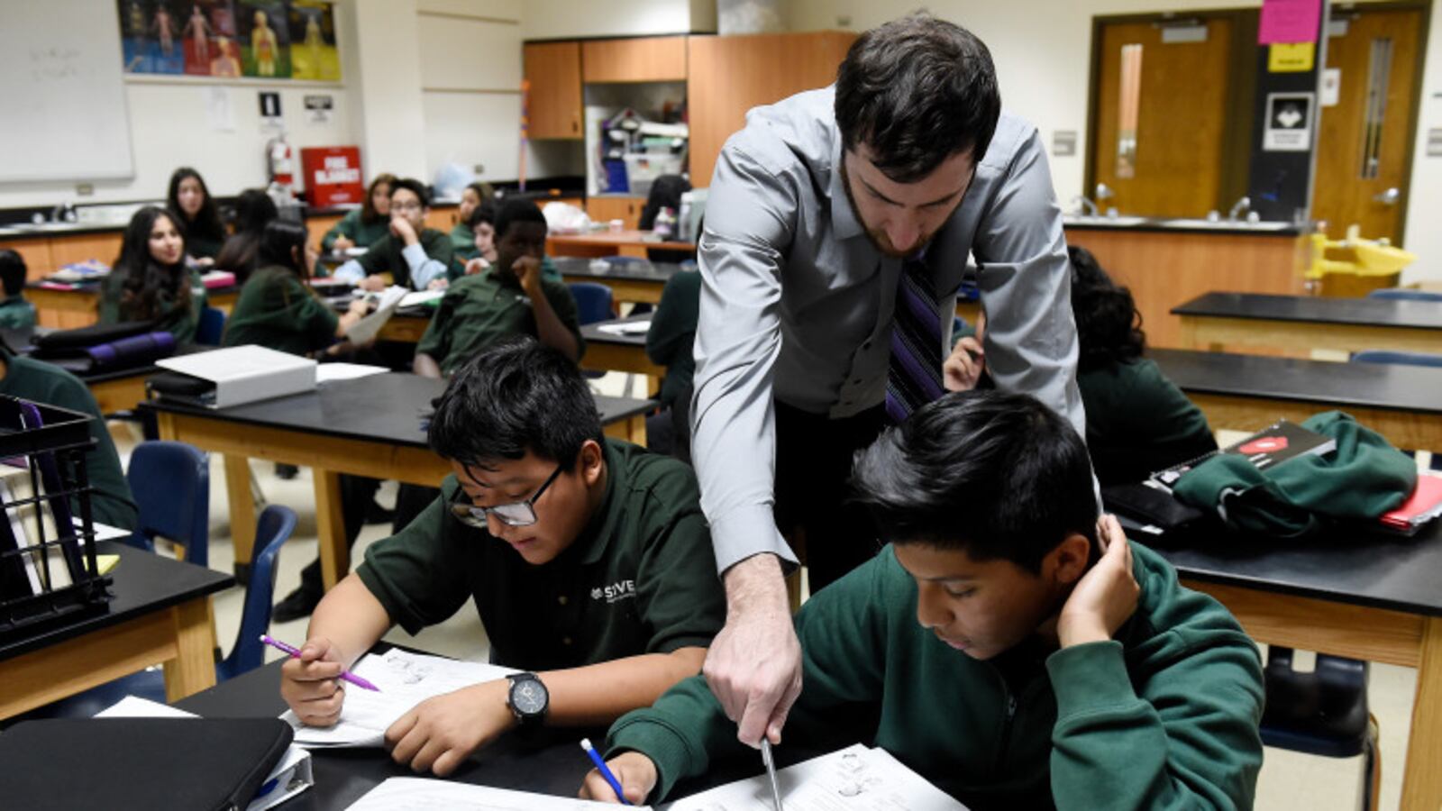 Justin Walker helps STRIVE Prep – Montbello students work through a problem during a seventh-grade biology class on January 30, 2017.