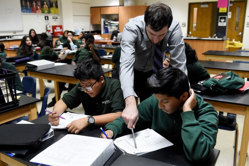 Justin Walker helps STRIVE Prep – Montbello students work through a problem during a seventh-grade biology class on January 30, 2017.