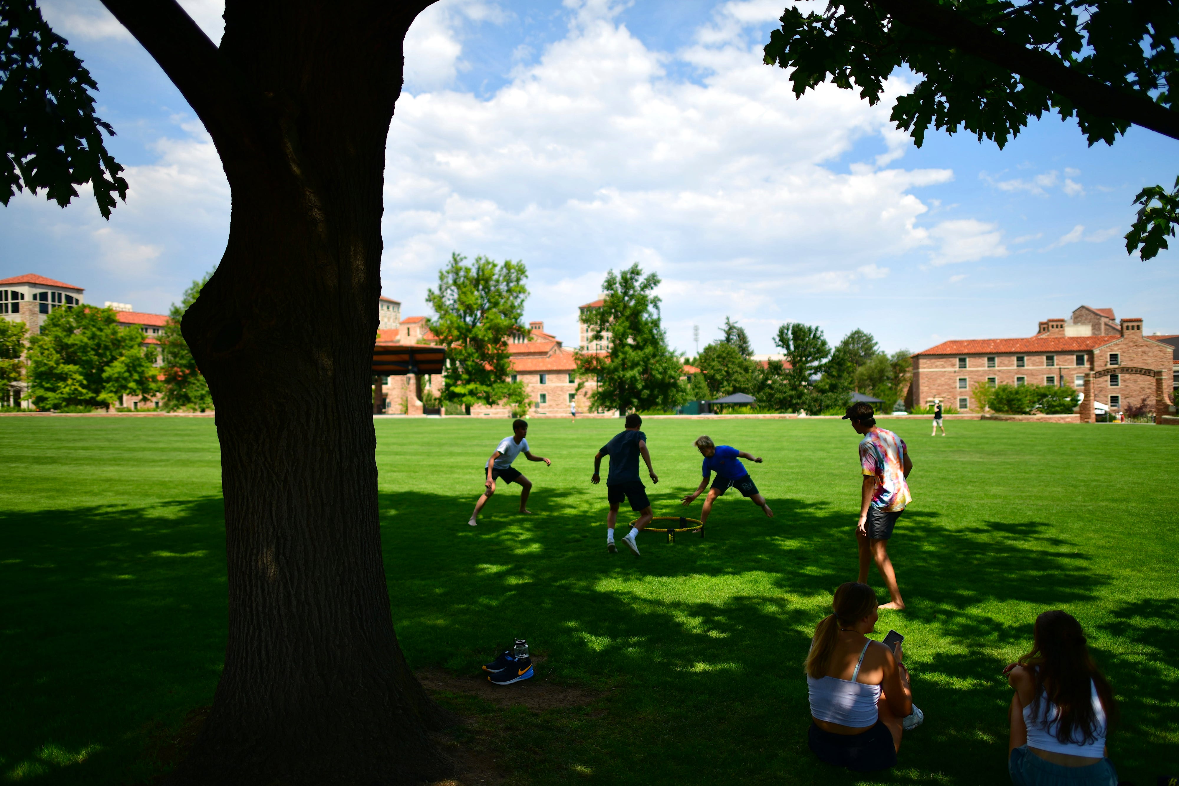 Students play on the lawn at the University of Colorado at Boulder campus on a bright sunny day.