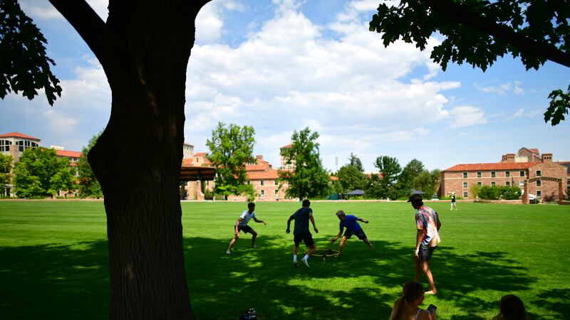 Students play on the lawn at the University of Colorado at Boulder campus on a bright sunny day.