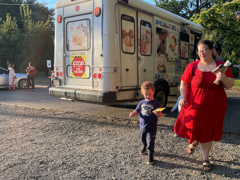 A photograph of a woman in a red dress walking with her young child.